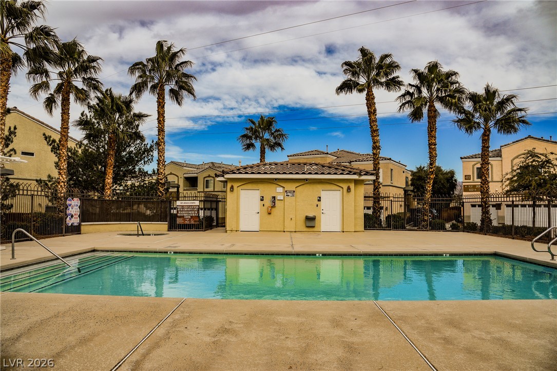 6320 Snap Ridge Street, Unit 201 North Las Vegas, NV 89081 - Photo 40 of 56 A refreshing pool awaits amidst a backdrop of palm trees and residential structures.