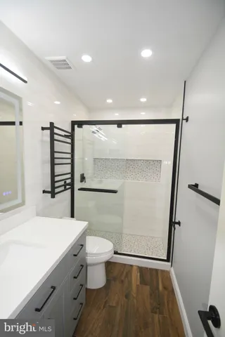 a bathroom with a sink a toilet a mirror and shower