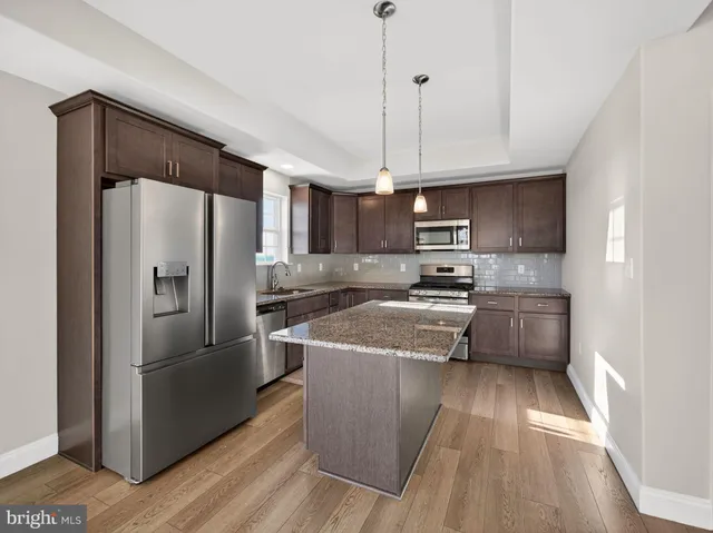 a kitchen with stainless steel appliances granite countertop a refrigerator a sink dishwasher a stove and a refrigerator