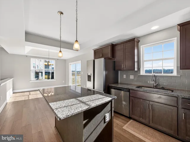 a kitchen with stainless steel appliances granite countertop a sink a stove and a wooden floors