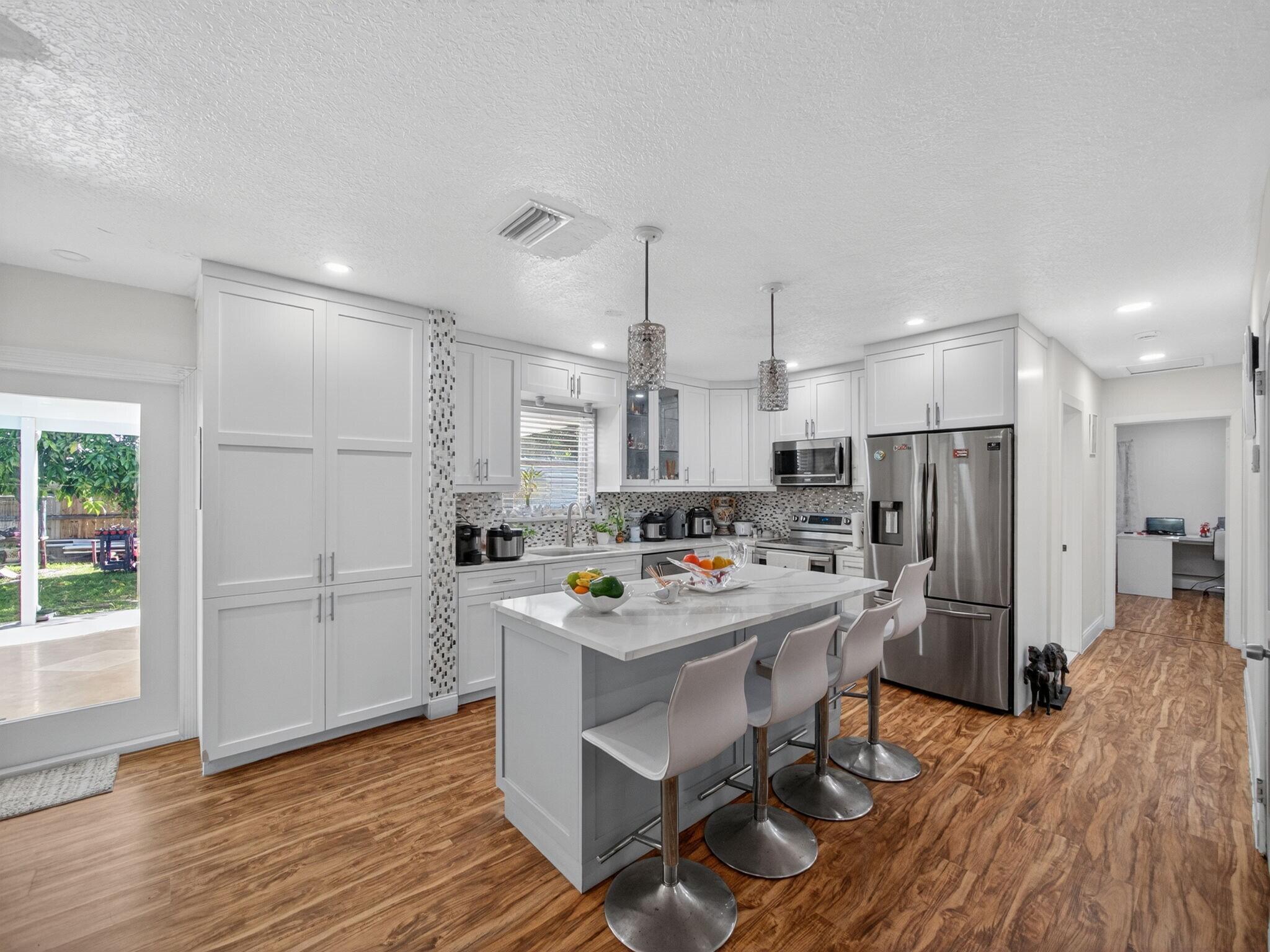 7026 Pine Tree Lane Lake Clarke Shores, FL 33406 - Photo 4 of 22 a kitchen with a sink a refrigerator and wooden floor