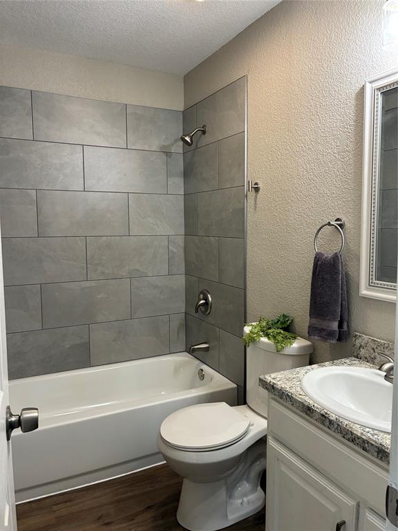 5066 East Highway 199 Springtown, TX 76082 - Photo 13 of 15 Full bath off hallway with a textured wall, vanity, a textured ceiling, vinyl flooring, and shower / bathtub combination