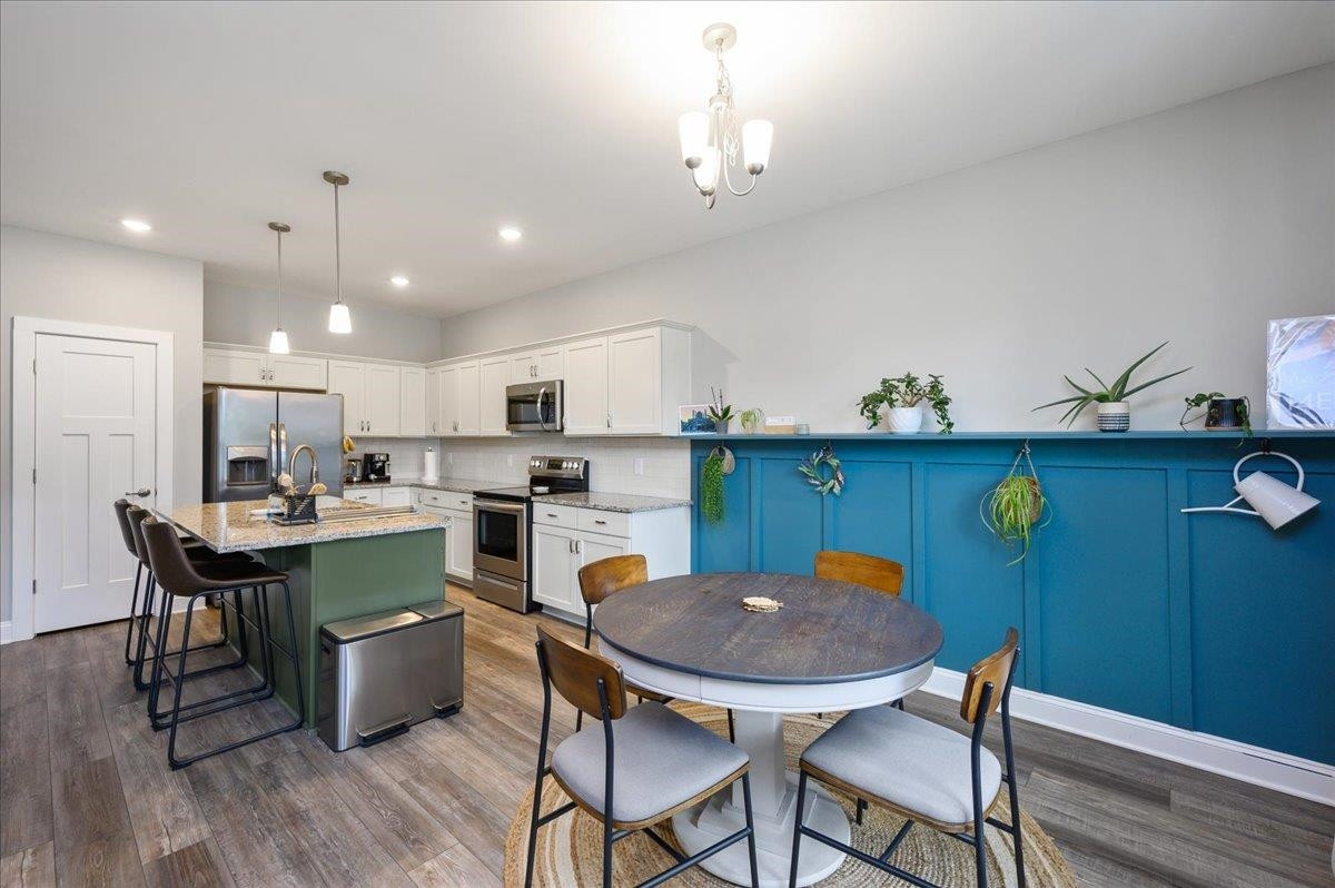 212 North Allen Road Wake Forest, NC 27587 - Photo 14 of 28 a kitchen with stainless steel appliances kitchen island granite countertop a dining table chairs and white cabinets