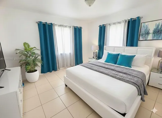 a bedroom with a large bed and a potted plant