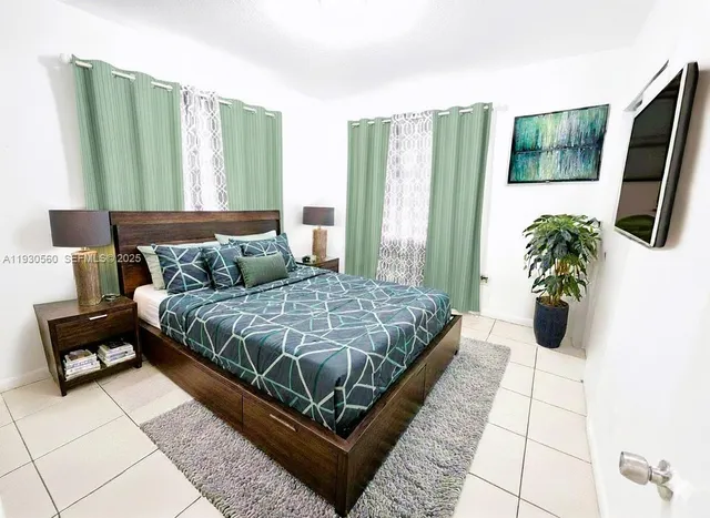 a bedroom with a bed lamp and a large window