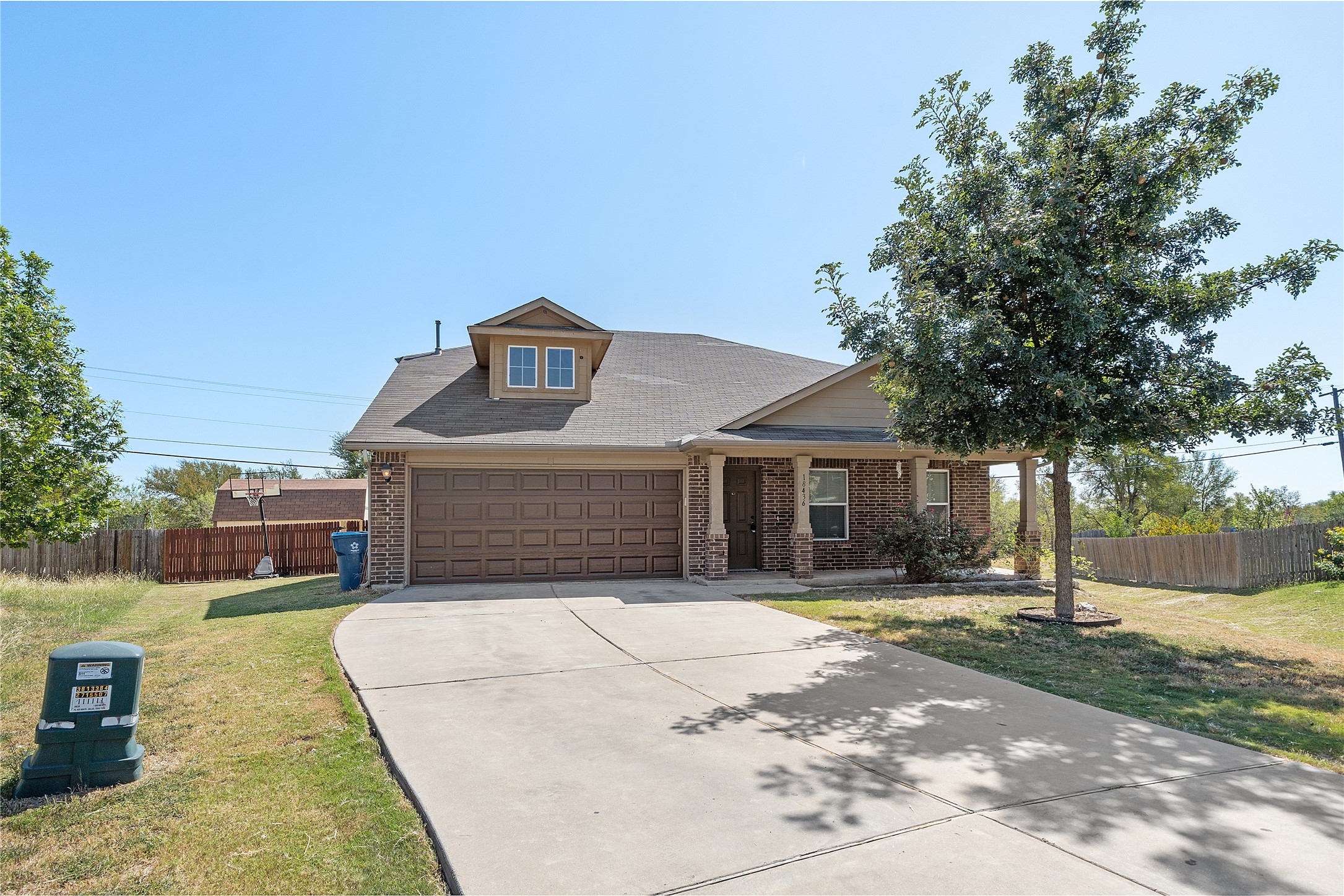 View of front of house featuring brick siding, a porch, roof with shingles, and concrete driveway