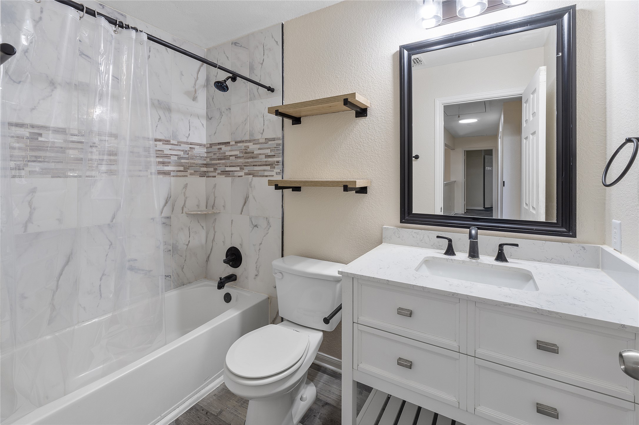 18436 Weatherby Lane Elgin, TX 78621 - Photo 14 of 23 Bathroom featuring a textured wall, shower / bathtub combination with curtain, vanity, and wood finished floors