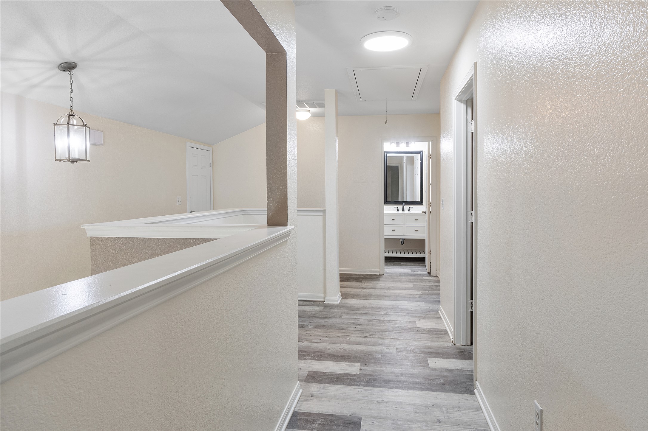 18436 Weatherby Lane Elgin, TX 78621 - Photo 17 of 23 Hallway with a textured wall, attic access, light wood finished floors, and vaulted ceiling