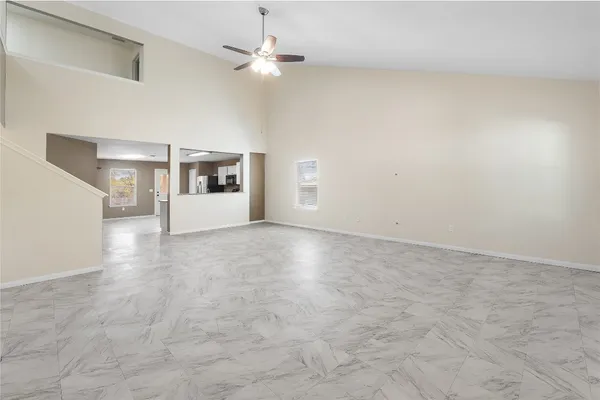 en empty room with windows and ceiling fan