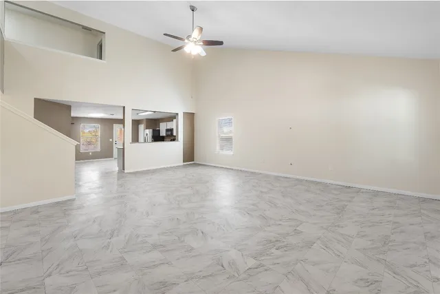 en empty room with windows and ceiling fan