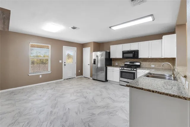 a kitchen with stainless steel appliances granite countertop a stove microwave and sink
