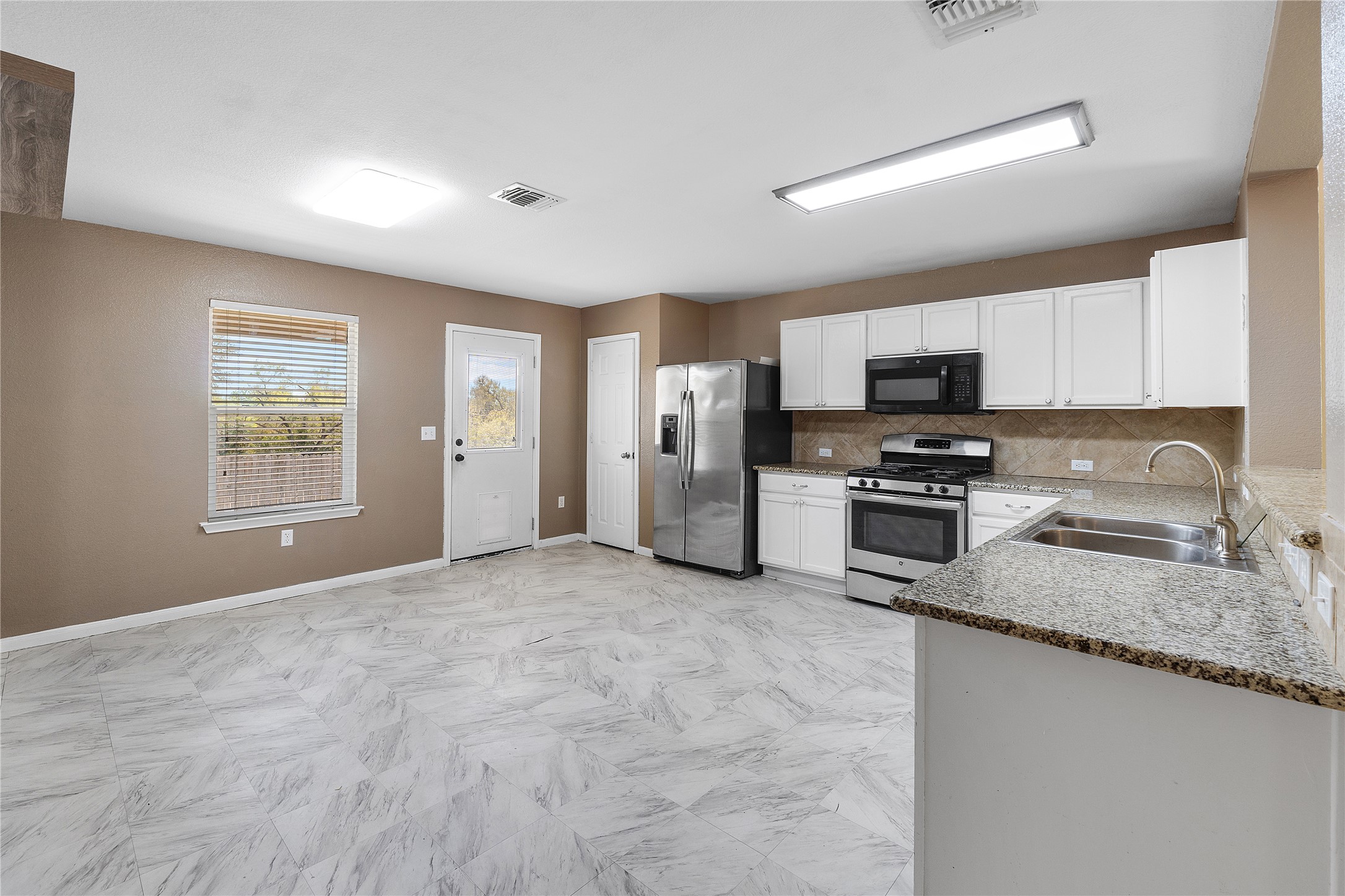 18436 Weatherby Lane Elgin, TX 78621 - Photo 4 of 23 Kitchen featuring decorative backsplash, stainless steel appliances, white cabinets, and light stone countertops