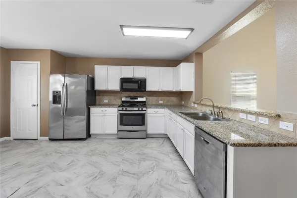 a kitchen with stainless steel appliances granite countertop a stove a sink dishwasher a refrigerator and a microwave
