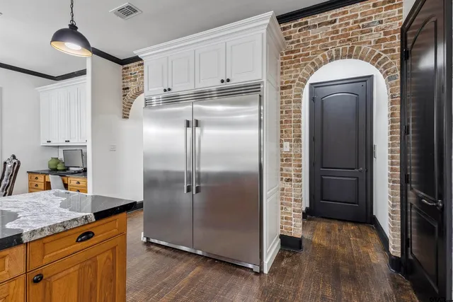 a kitchen with stainless steel appliances granite countertop a refrigerator a stove and a sink with wooden floor