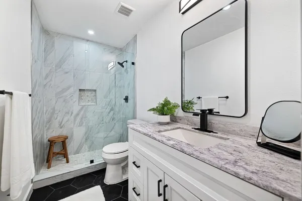 a bathroom with a granite countertop sink mirror vanity and toilet