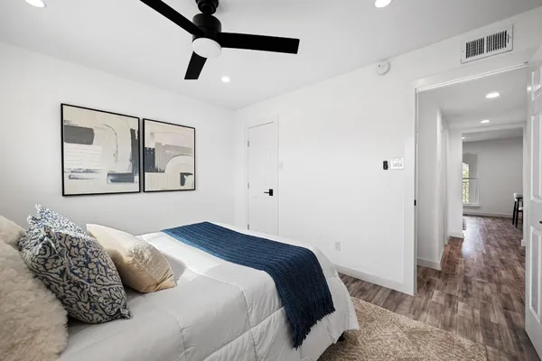 a bedroom with a large bed and a chandelier fan