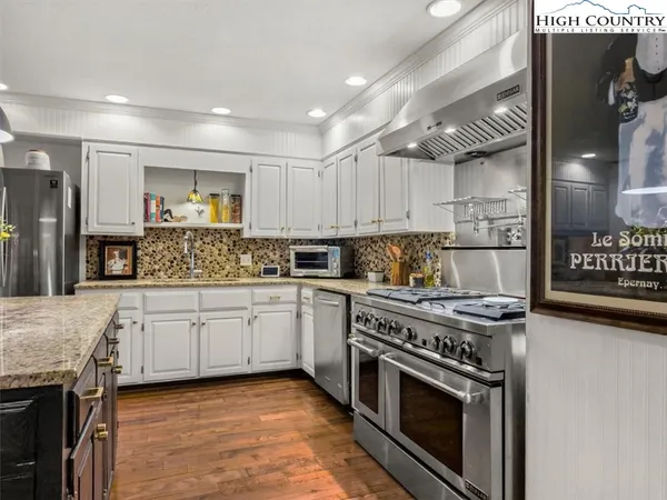 a kitchen with stainless steel appliances granite countertop a sink a stove and a wooden floors