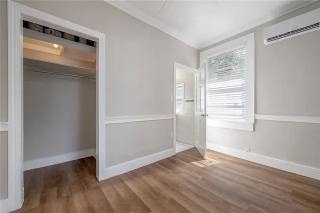 an empty room with wooden floor cabinet and windows