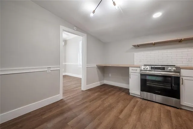 an empty room with wooden floor fireplace and windows