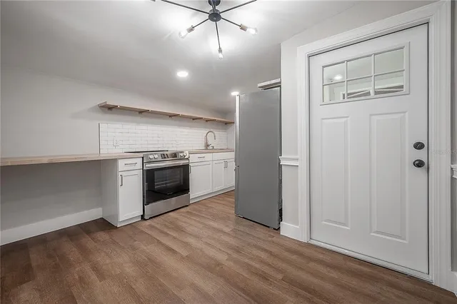 an empty room with wooden floor cabinet and windows