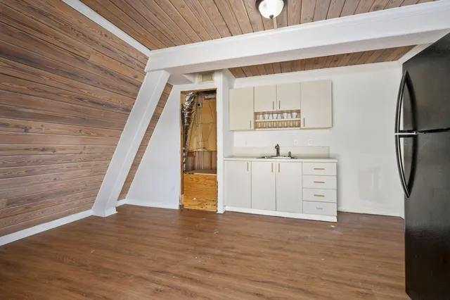 a view of a kitchen with refrigerator and wooden floor