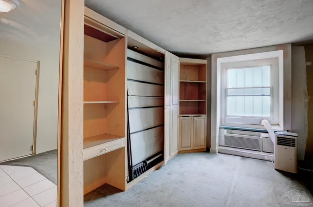 a view of an empty room with cabinet and mirrors