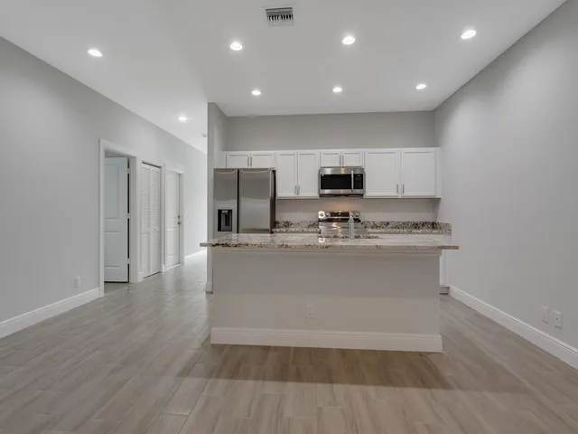 a view of kitchen with stainless steel appliances granite countertop a stove a sink and a refrigerator