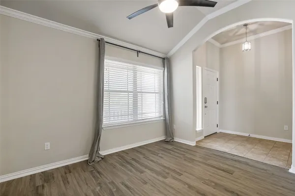 a view of an empty room with wooden floor and a window