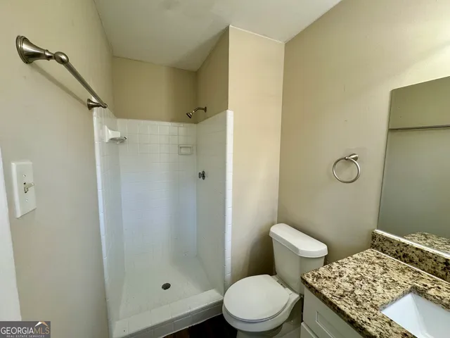 a bathroom with a granite countertop toilet a sink and shower