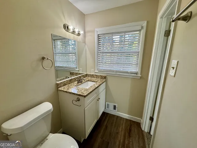 a bathroom with a granite countertop toilet sink and mirror