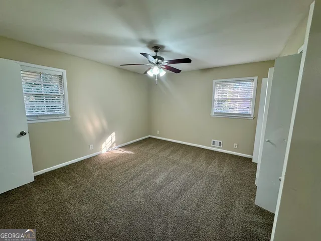 an empty room with windows and fan