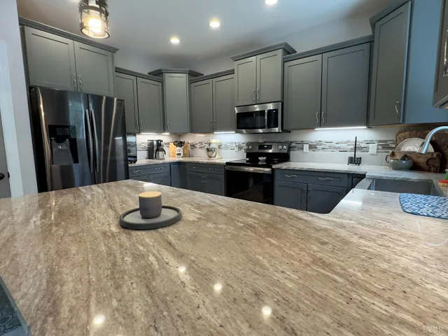 a kitchen with stainless steel appliances granite countertop a sink refrigerator stove microwave and cabinets