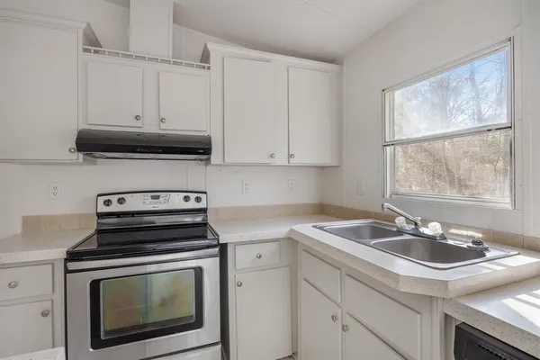 a kitchen with cabinets a stove a sink and a microwave