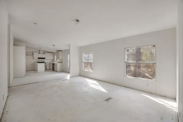 a view of empty room with a kitchen and refrigerator