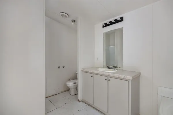 a bathroom with a granite countertop sink a toilet and a mirror
