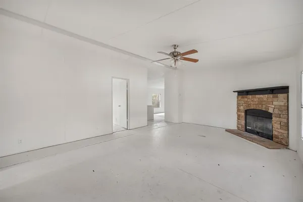 an empty room with fan and a fireplace