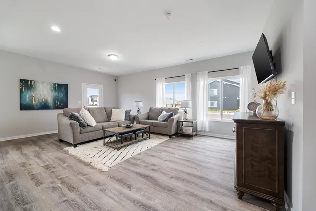 a living room with furniture a flat screen tv and a floor to ceiling window