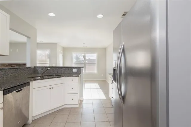 a kitchen with granite countertop a refrigerator and white cabinets