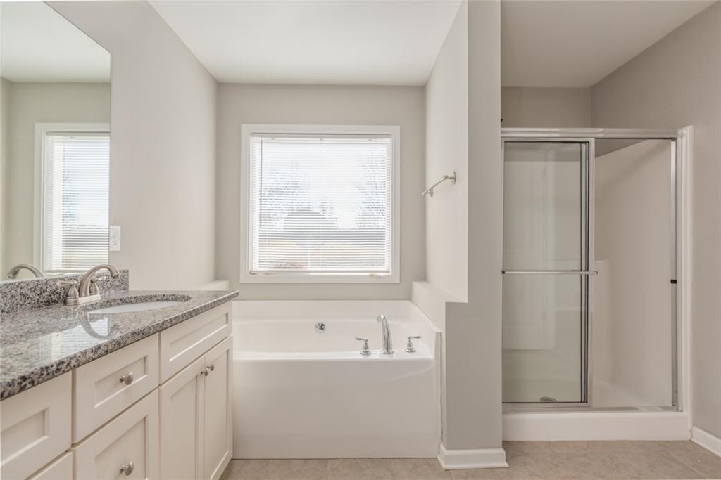 82 Gray Field Court Jefferson, GA 30549 - Photo 21 of 30 a bathroom with a granite countertop sink a mirror and a bathtub