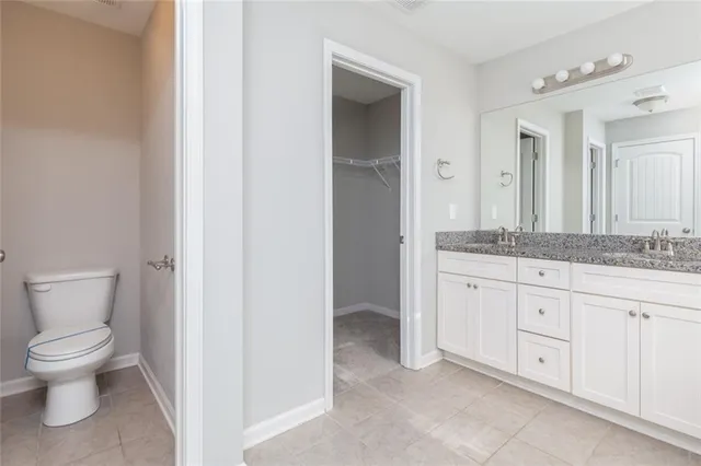 a spacious bathroom with a granite countertop toilet a sink and a mirror