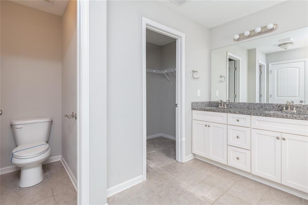 82 Gray Field Court Jefferson, GA 30549 - Photo 22 of 30 a spacious bathroom with a granite countertop toilet a sink and a mirror