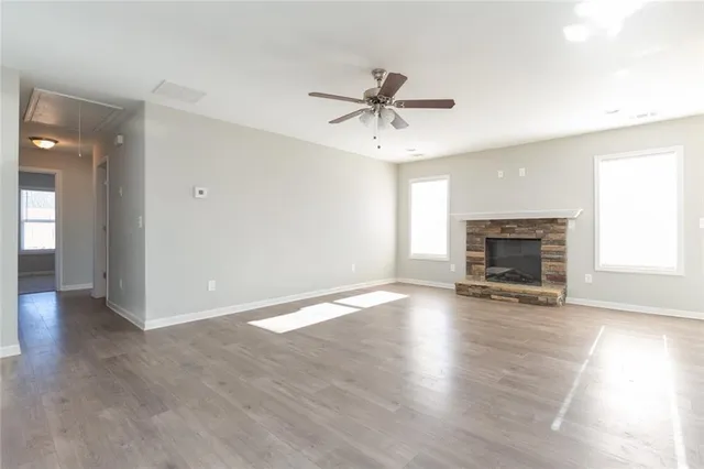 an empty room with wooden floor fireplace and windows