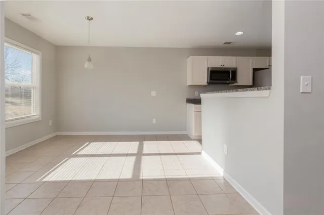 a view of an empty room with a window and a kitchen