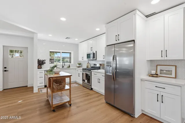 a kitchen with cabinets wooden floor and stainless steel appliances