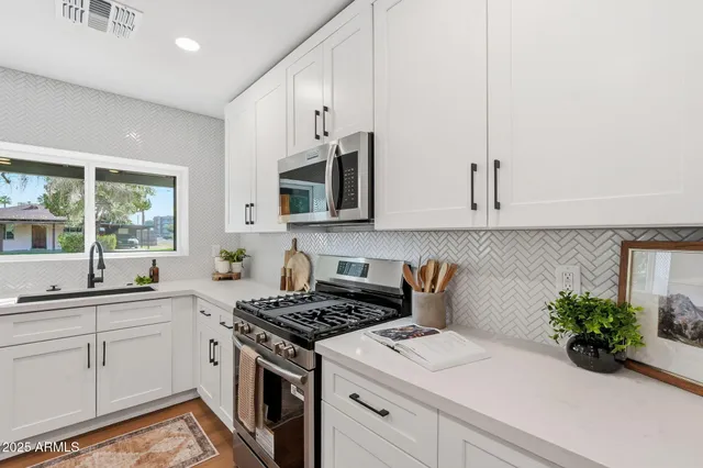 a kitchen with stainless steel appliances white cabinets and a stove top oven