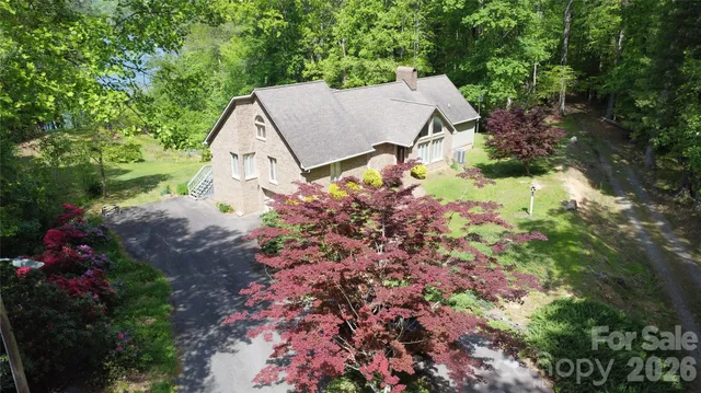 an aerial view of a house with a yard and a large tree