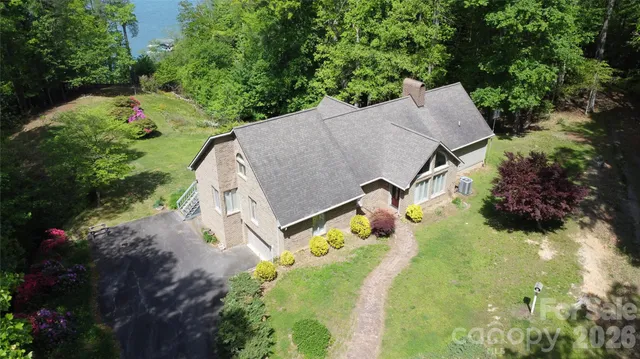 an aerial view of a house with a yard and trees all around