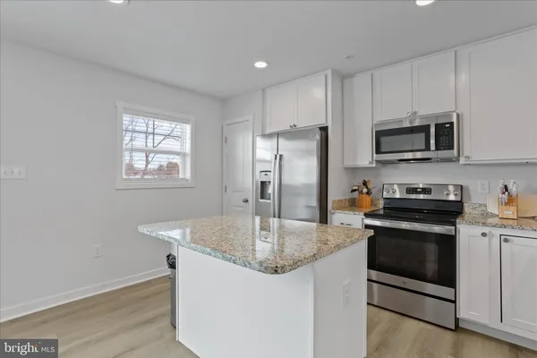 a kitchen with stainless steel appliances granite countertop a sink a microwave a refrigerator and cabinets