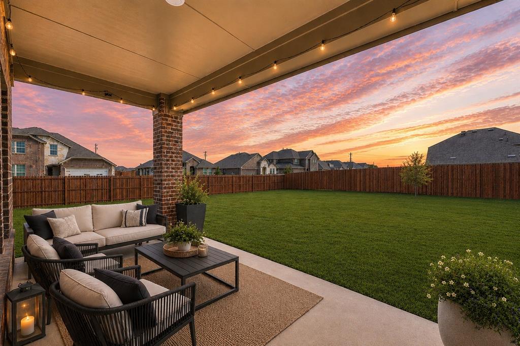 9828 Quail Pointe Road Aubrey, TX 76227 - Photo 2 of 23 Covered patio with string lighting and brick columns, extending to a spacious grass lawn and wood fencing