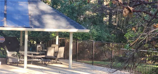 a view of a white house with large tree and wooden fence